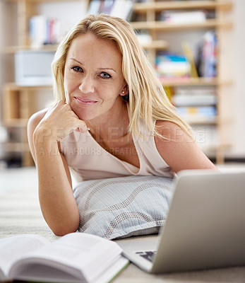 Buy stock photo Portrait of a beautiful mature woman lying on her living room floor using a laptop