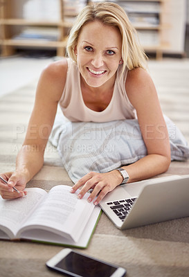 Buy stock photo Portrait of a beautiful mature woman lying on her living room floor doing some research