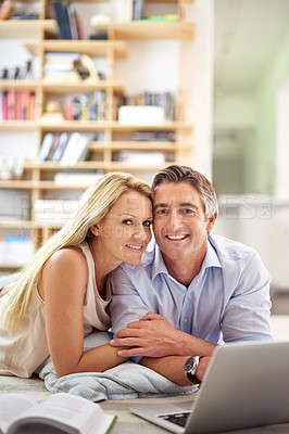 Buy stock photo Portrait of a mature couple lying on their living room floor doing some online research