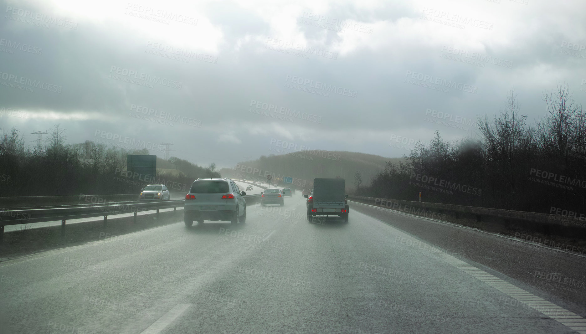 Buy stock photo Cars driving on a wet and rainy day. Staying safe and avoiding accidents on a highway. Asphalt road through the countryside on a cold and misty day, surrounded by trees and open grassland in Germany