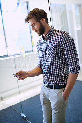 Buy stock photo Cropped shot of a handsome businessman using his cellphone at the office