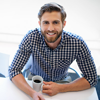 Buy stock photo Portrait of a handsome businessman sitting with a cup of coffee at his office desk