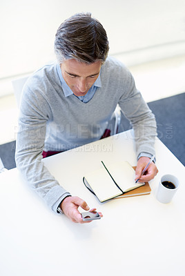 Buy stock photo Cropped shot of a businessman using his cellphone while working at his office desk