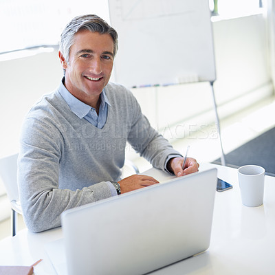 Buy stock photo Portrait of a mature businessman working on his laptop at the office