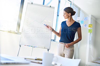 Buy stock photo Shot of an attractive young businesswoman pointing to a graph on a white board