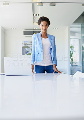 Buy stock photo A young businesswoman at the office standing behind a table with a laptop on it