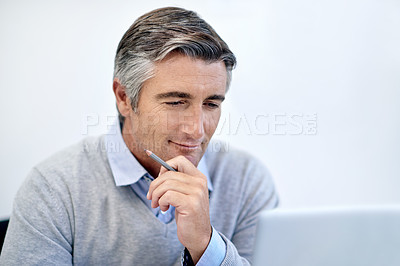 Buy stock photo Shot of a mature businessman looking thoughtfully at his laptop screen