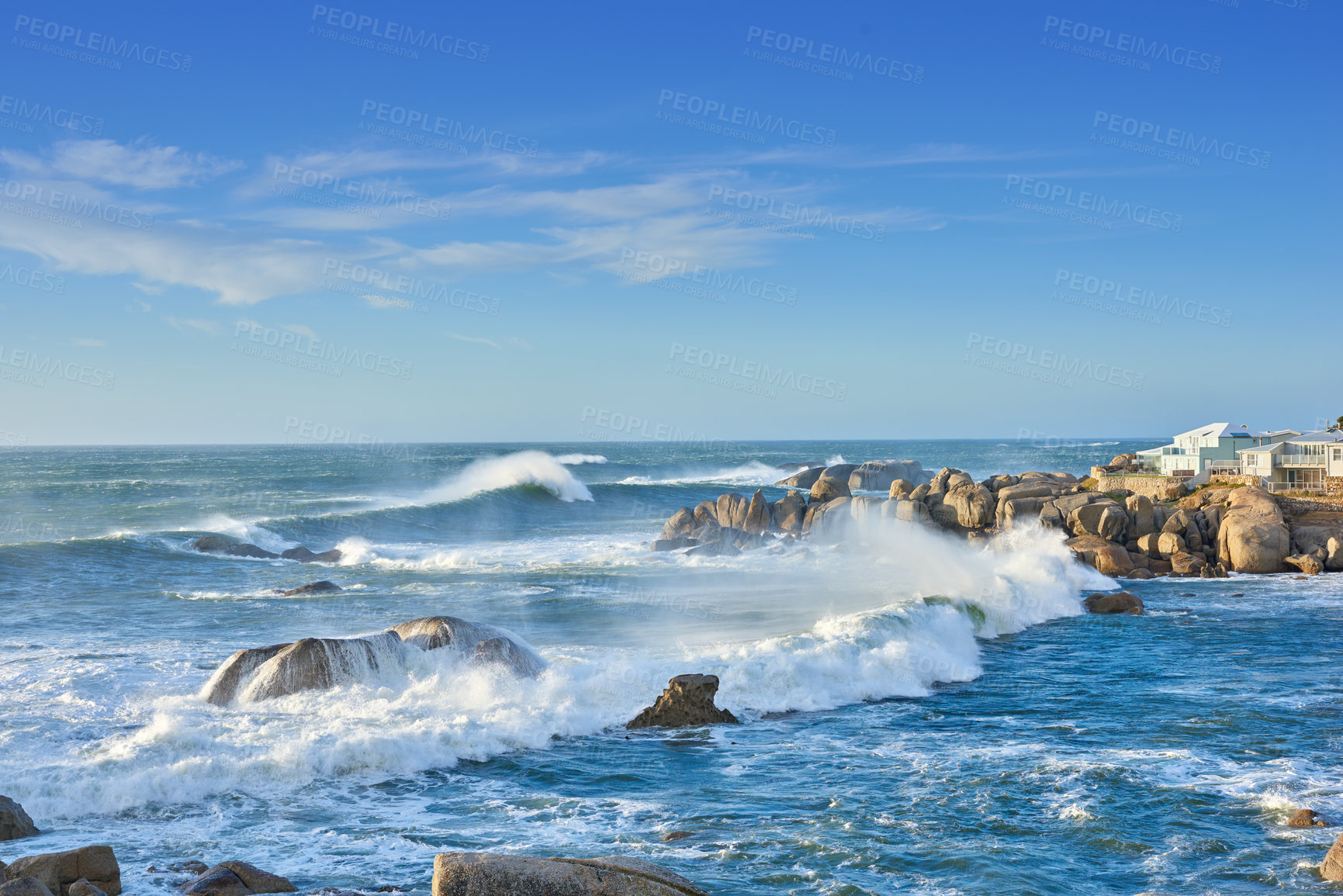 Buy stock photo A rocky coastline in the Cape Province, South Africa. Ocean waves crashing on coastal rocks on a sunny summer day with blue clear skies and a scenic tropical landscape beachfront in the Western Cape
