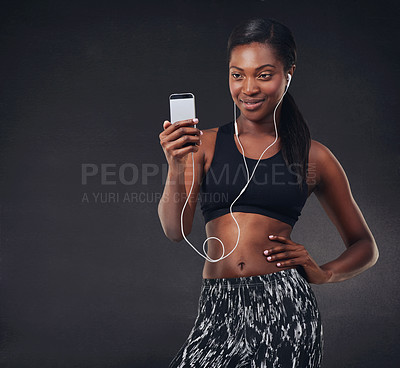 Buy stock photo Studio shot of a beautiful young woman listening to music during her workout against a black background