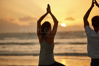 Buy stock photo Rearview shot of a couple doing yoga on the beach at sunset