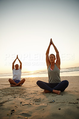Buy stock photo Shot of a couple doing yoga on the beach at sunset