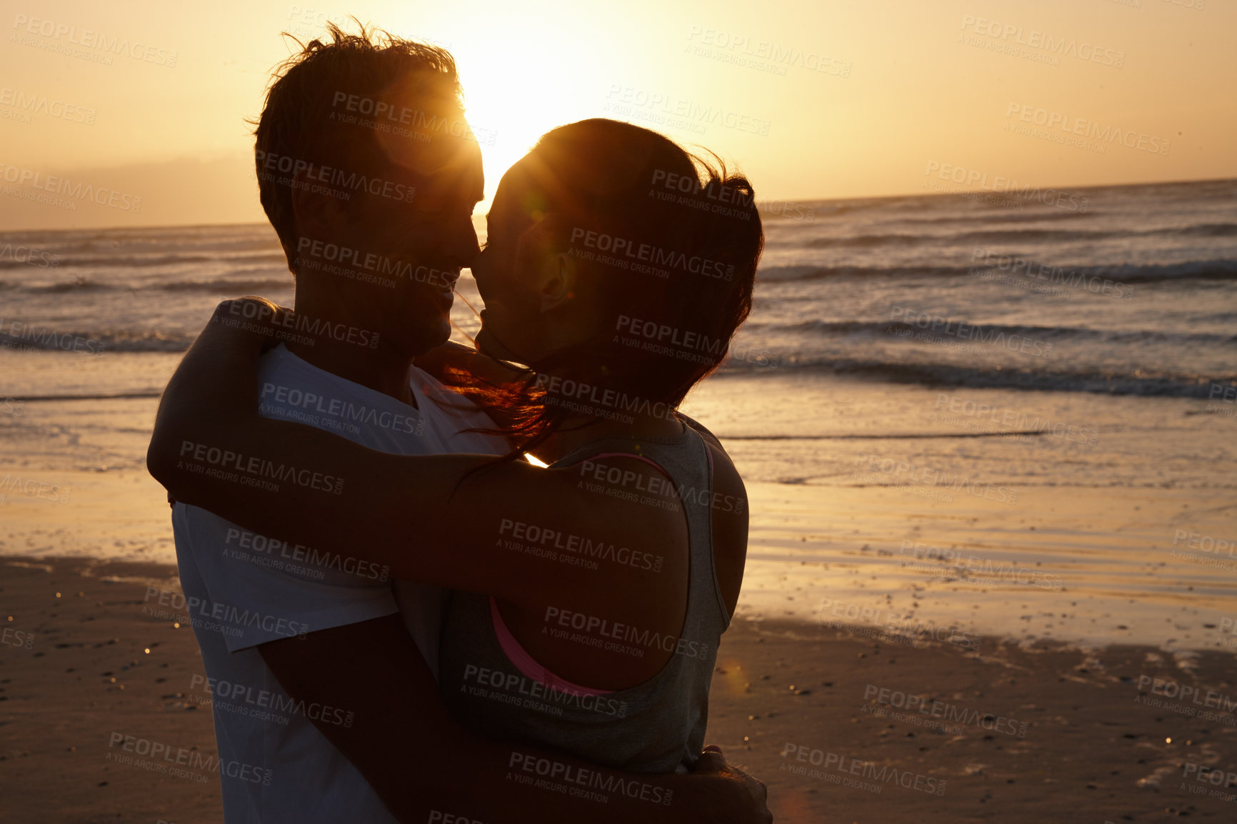 Buy stock photo Silhouette of a couple being romantic at the beach at sunset