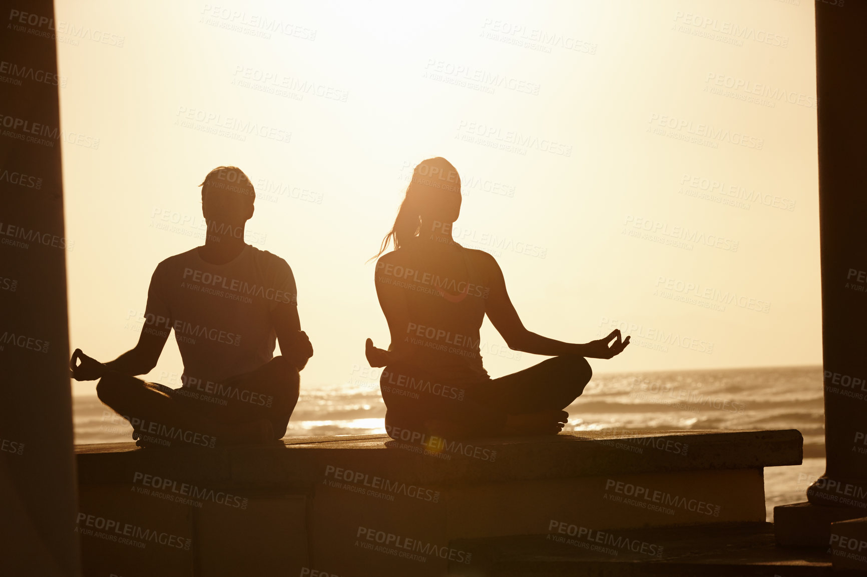 Buy stock photo Shot of a couple meditating by the sea at sunset