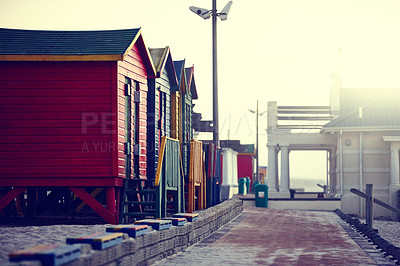 Buy stock photo Shot of a wendy houses on a waterfront walkway in the morning