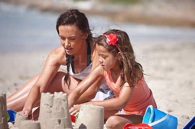Buy stock photo Shot of a happy mother and daughter building sandcastles together at the beach