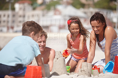 Buy stock photo Shot of a happy family building sandcastles together at the beach