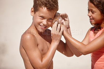 Buy stock photo Shot of a little girl holding a conch shell against her brother's ear