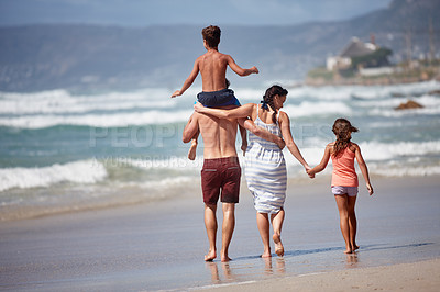 Buy stock photo Rearview shot of a family walking along the beach
