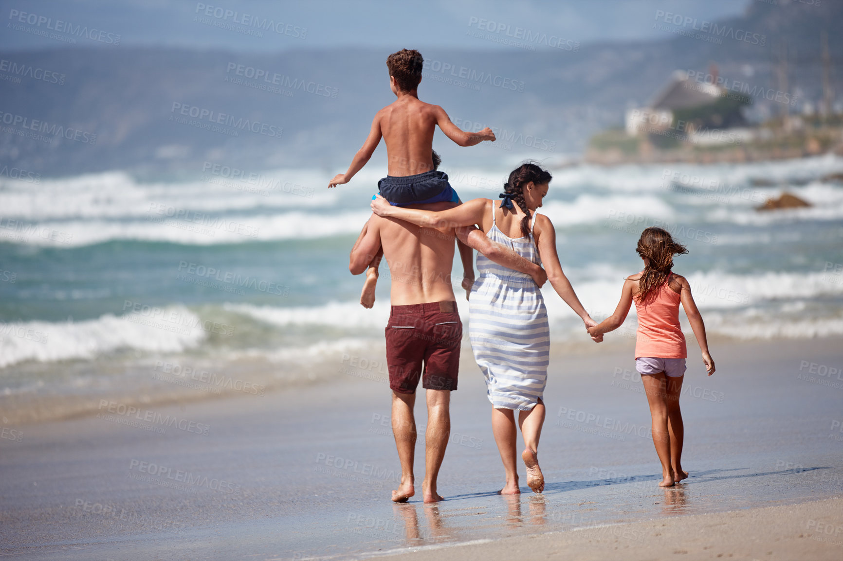 Buy stock photo Rearview shot of a family walking along the beach