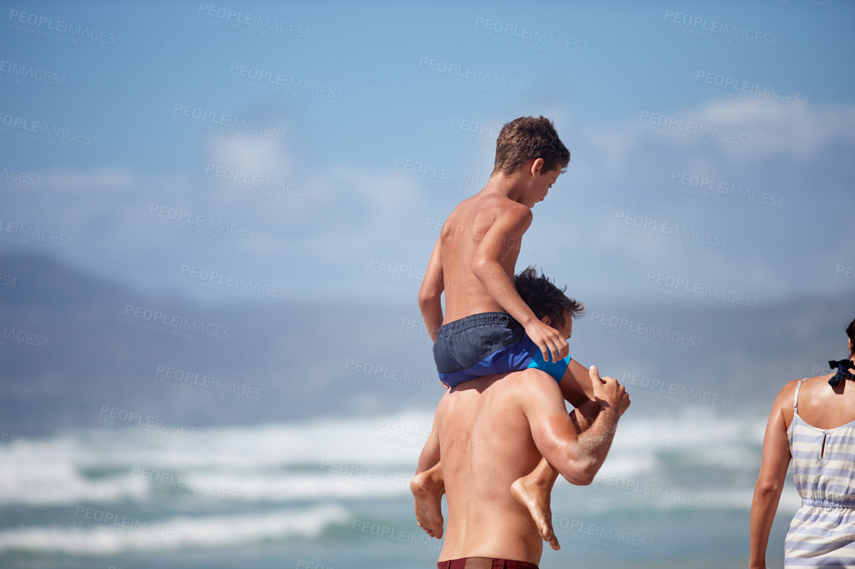 Buy stock photo Shot of a father giving his son a piggyback ride at the beach