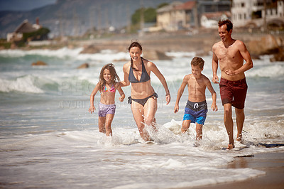Buy stock photo Shot of a family playing in the waves at the beach