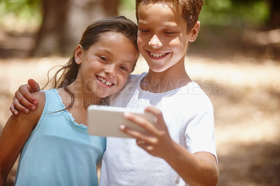 Buy stock photo Shot of a brother and sister taking a selfie together on a camping trip in the forest