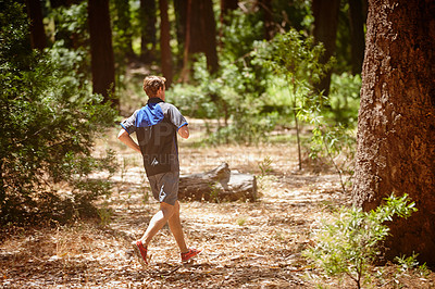 Buy stock photo Rearview shot of a man jogging in a forrest