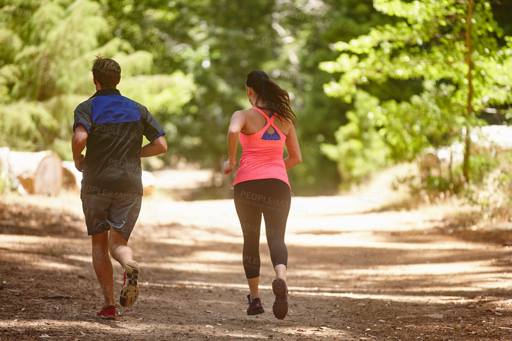 Buy stock photo Rearview shot of a couple jogging in the forest