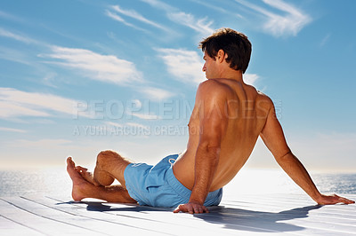Buy stock photo Ocean, relax and shirtless man on a deck with a view of the water in summer while on holiday or vacation. Freedom, sea or sky and the body of a young tourist tanning outdoor on a pier with space