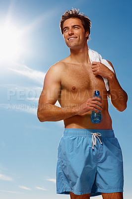 Buy stock photo Man, shirtless and water bottle or towel for workout with health body, fitness or happiness on vacation. Model, smile or natural glow with drink for hydration or post exercise in sunshine with shorts