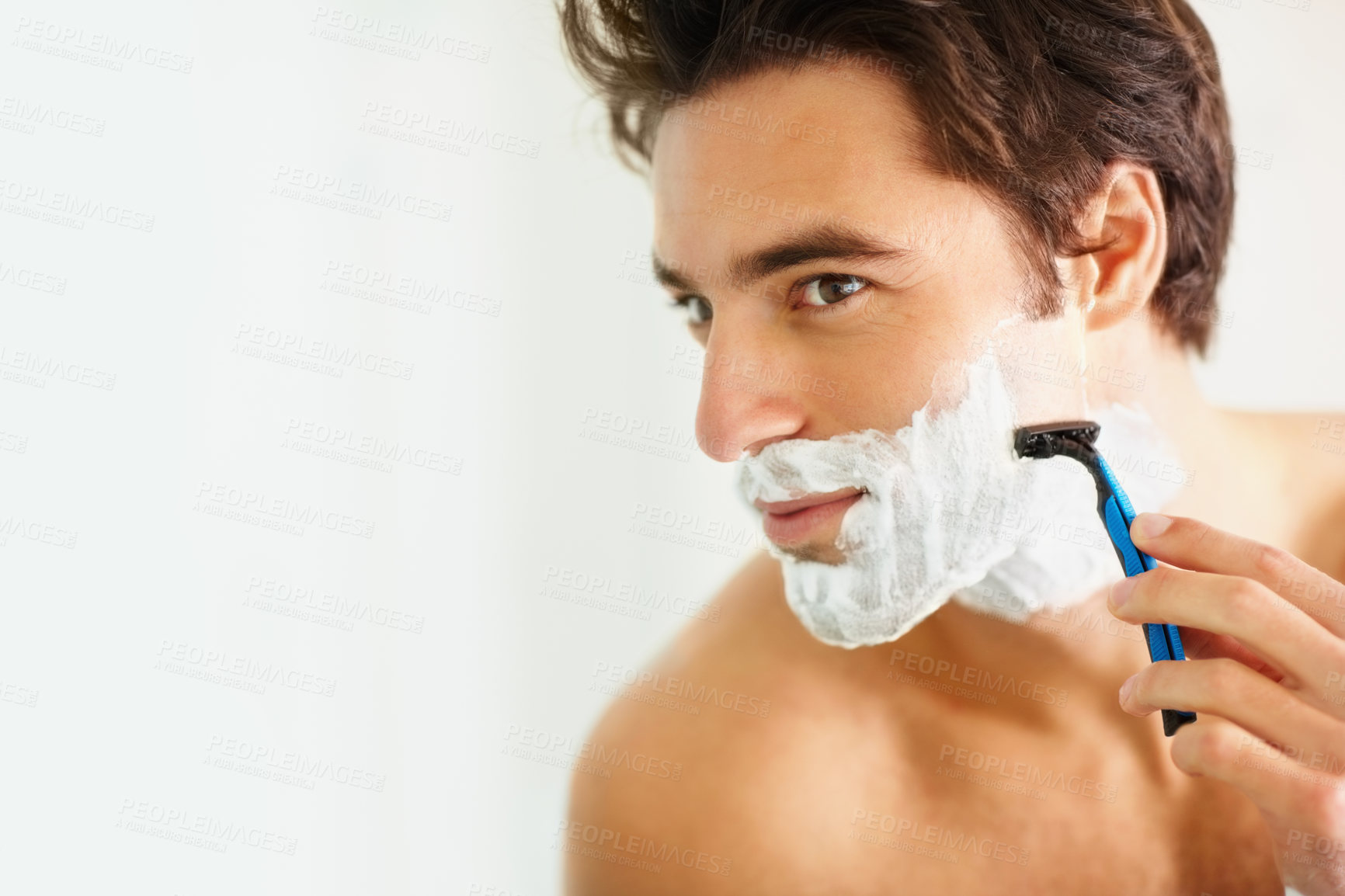 Buy stock photo Face, shave and razor with a man in the bathroom of his home for grooming or morning routine. Skincare, beauty and foam with a young person in his apartment, shaving his beard for hair removal