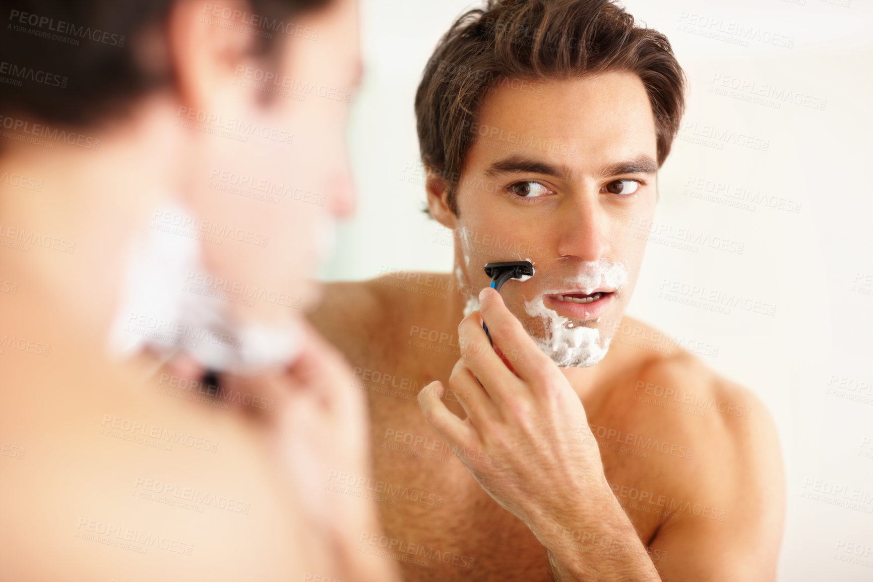 Buy stock photo Face, mirror and shave with a man in the bathroom of his home for grooming or morning routine. Skincare, reflection and razor with a young person in his apartment, shaving his beard for hair removal
