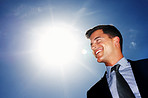 Cheerful businessman looking at copyspace against sky