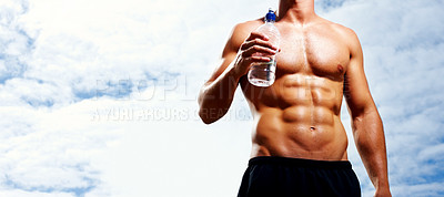Buy stock photo Mid section of masculine young man holding a bottle of water against sky
