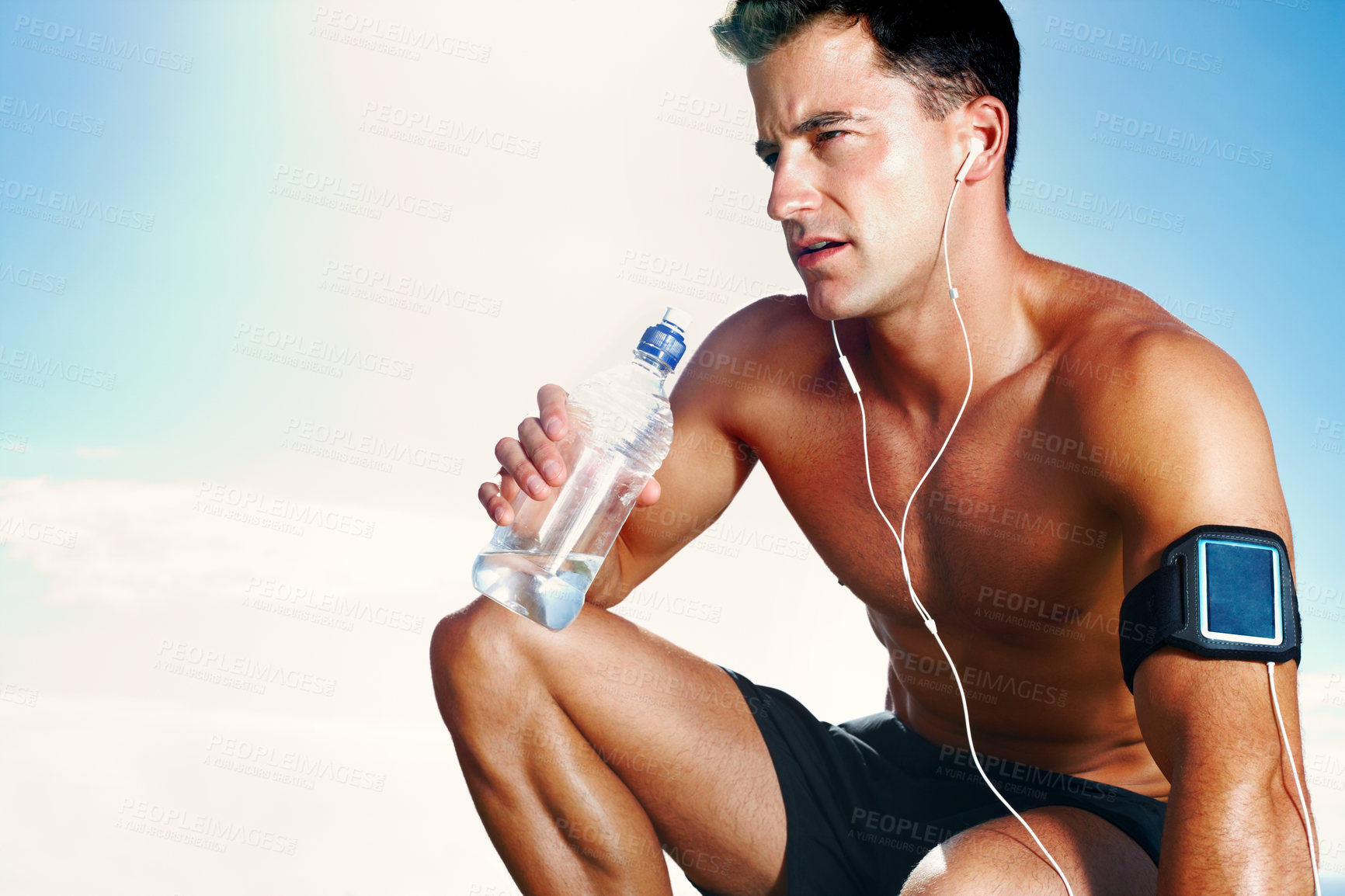 Buy stock photo Water, tired and man on field for workout, earphones and sunlight with bottle and summer. Training, cardio and exercise for male person or athlete, running and park for fitness on grass with music