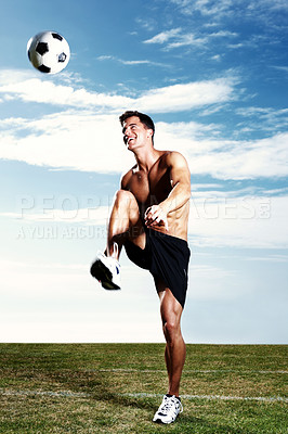 Buy stock photo Portrait of a muscular soccer player kicking the soccer ball against the sky
