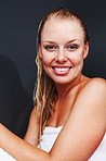 Happy woman wrapped in a bath towel against a black background