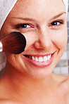 Closeup of a happy woman applying make up to face after a bath