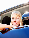 Smiling thoughtful female with head out of a car