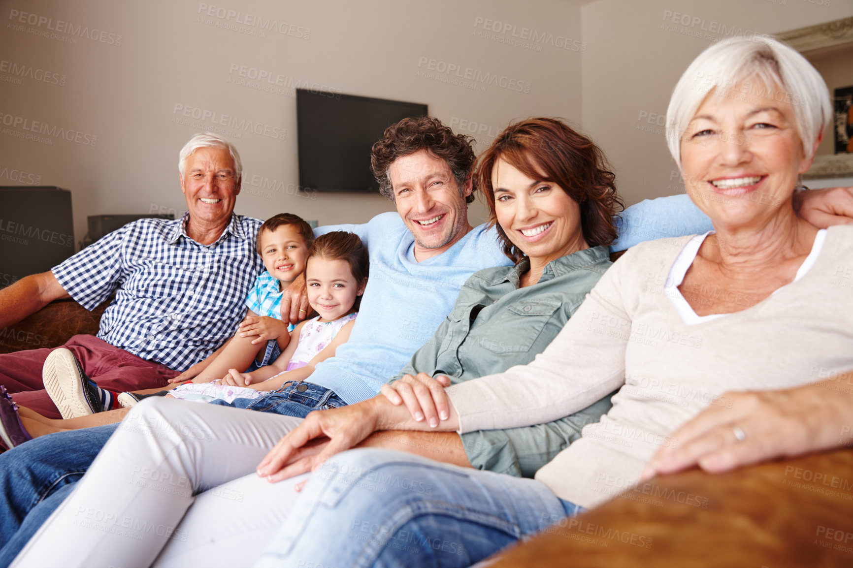 Buy stock photo Portrait of a happy multi-generational family sitting together on a sofa