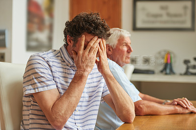 Buy stock photo Shot of a man looking upset while sitting beside his father