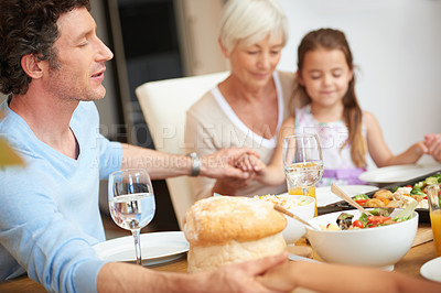 Buy stock photo Shot of a family praying together before having a meal