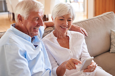 Buy stock photo Shot of a senior couple using a cellphone together