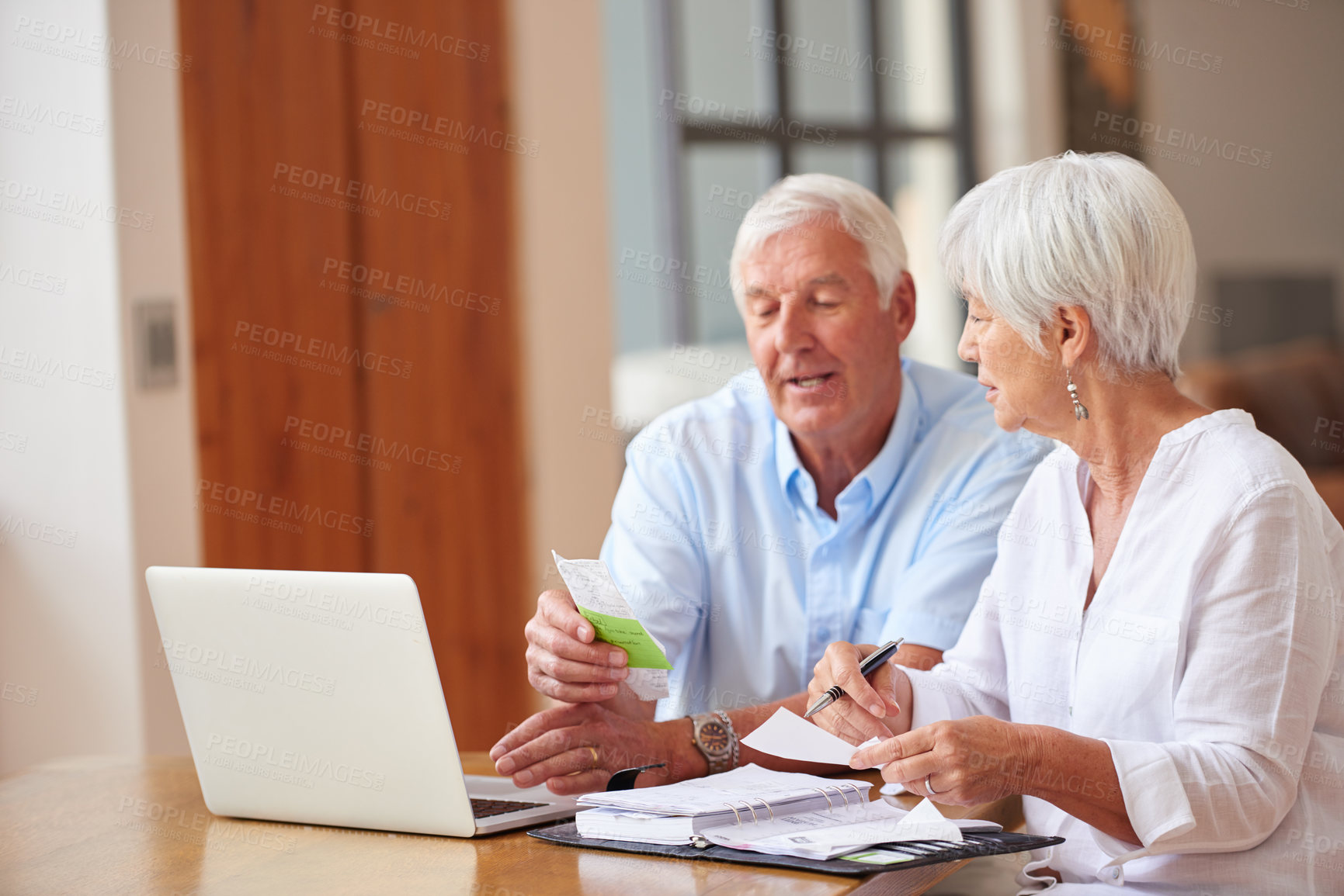 Buy stock photo Shot of a senior couple going over some paperwork while using a laptop