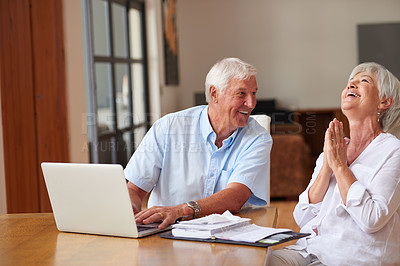 Buy stock photo Shot of a senior couple going over some paperwork while using a laptop