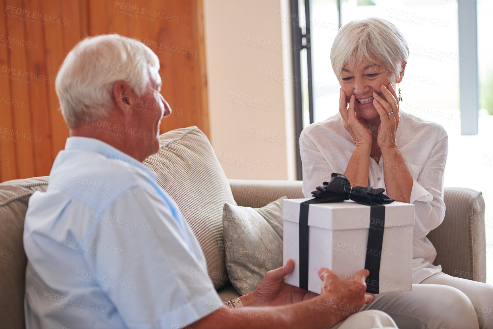 Buy stock photo Shot of a senior man giving his wife a gift