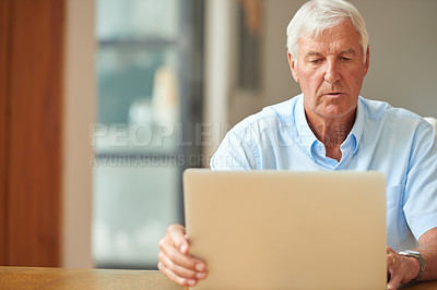 Buy stock photo Shot of a senior man using a laptop at home