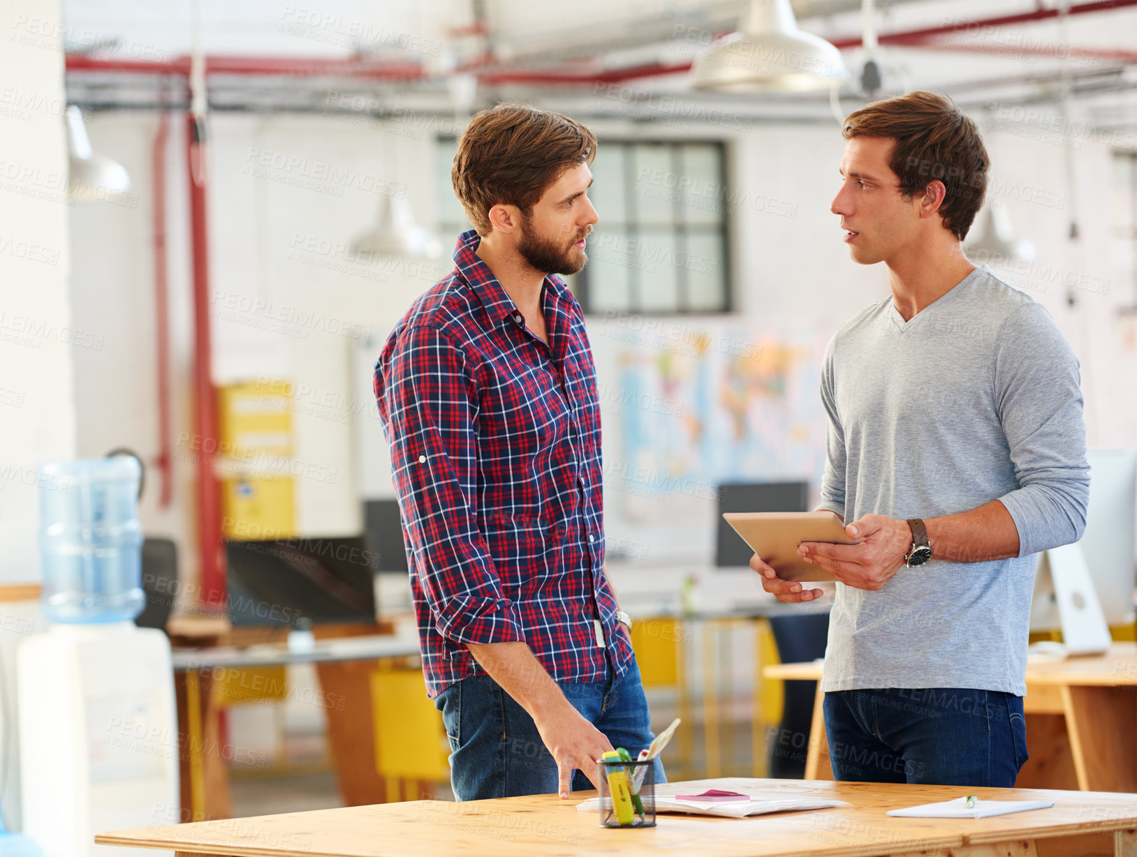 Buy stock photo Shot of two coworkers using a digital tablet together in an office