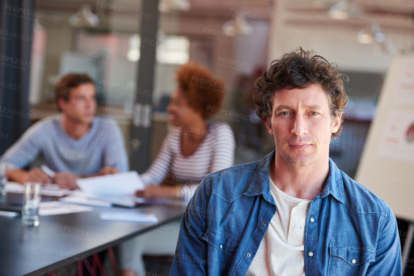 Buy stock photo Portrait of a confident man sitting in a boardroom with his colleagues