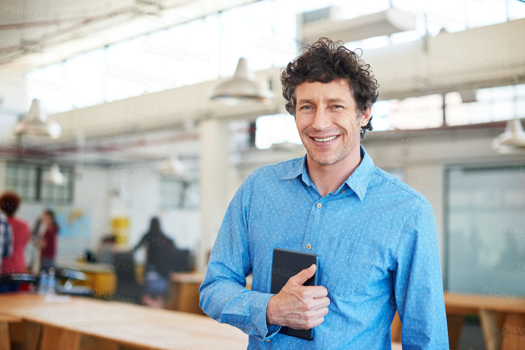 Buy stock photo Cropped shot of a handsome businessman working in the office with his colleagues in the background